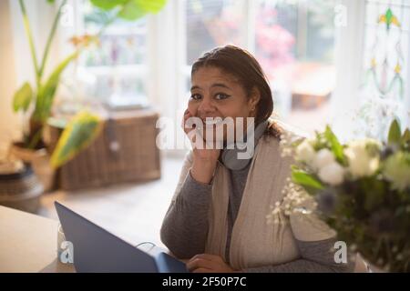 Portrait happy woman working from home at laptop