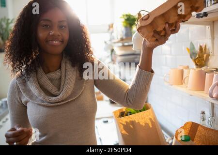 Portrait smiling woman unpacking groceries in kitchen Stock Photo
