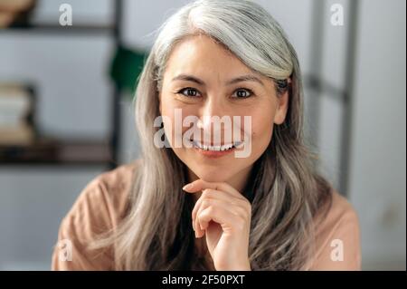 Close-up portrait of a beautiful successful mature asian business woman, self-confident gray haired lady in casual stylish wear, looking directly at the camera with friendly smile Stock Photo