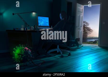 Man working from home at desk chained to Covid-19 bacterium Stock Photo