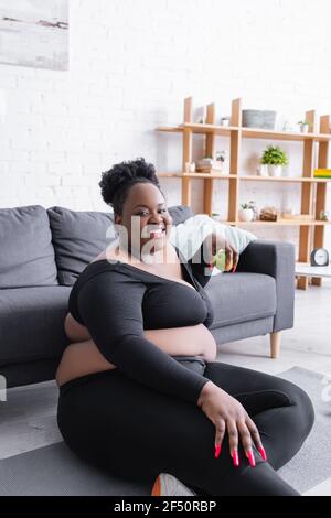 african american plus size woman in sportswear sitting in yoga pose near  laptop in living room Stock Photo - Alamy