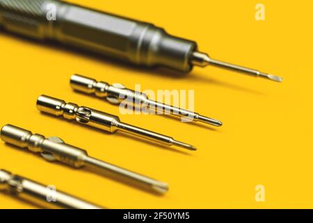 Screwdriver with replaceable metal bits on yellow background Stock Photo