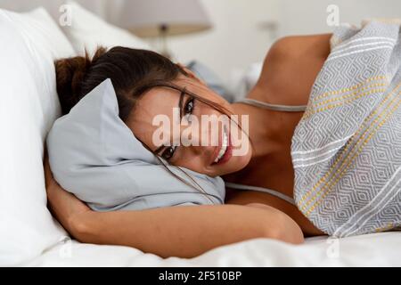 Caucasian woman lying on bed looking at the camera and smiling Stock Photo