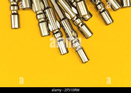 Replaceable bits close-up view, a pile of metal screwdriver bits on yellow background Stock Photo