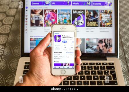 In this photo illustration the Twitch app in App Store seen displayed on a smartphone screen and a Twitch website displayed on laptop in the backgroun Stock Photo