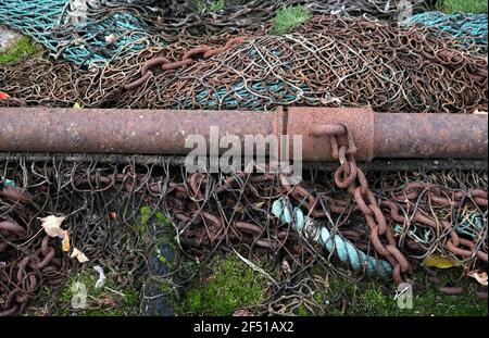 Shot of a rusty metal pipe set down on a big pile of a fishing net with chains hanging from it. Stock Photo