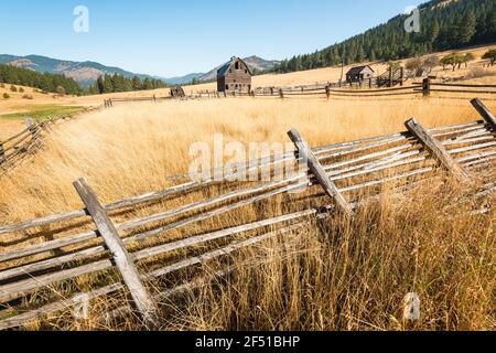 Late Fall scene in rural Eastern Washington State with broken fence falling over and an old barn near Cle Elum and the Cascade Mountains Stock Photo