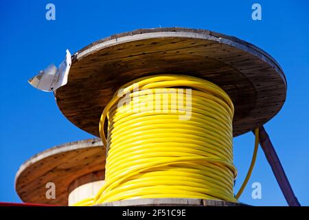 large wooden rolls with yellow wires wrapped around Stock Photo