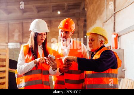 Group of engineers and workers discuss production plans Stock Photo