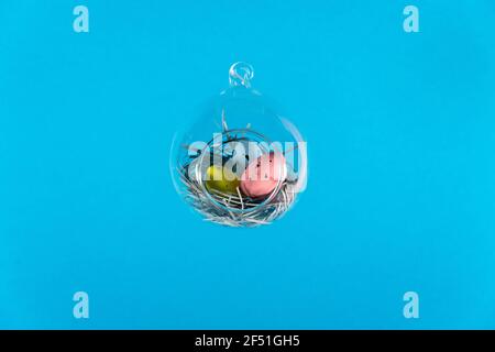 Three eggs in a floating glass nest. Blue background. Creative Easter concept Stock Photo