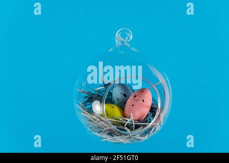 Three eggs in a floating glass nest. Blue background. Creative Easter concept Stock Photo