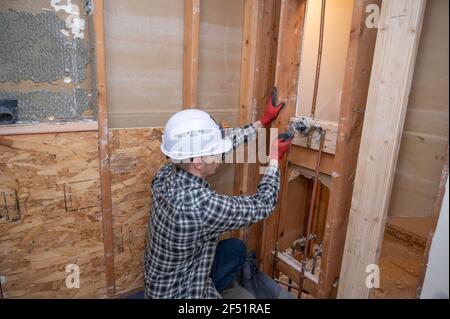 Plumber working on pipe in shower that has been demolished for renovation Stock Photo