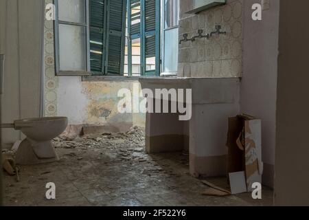 Interior of an abandoned dark bathroom in a  building, the only light comes in through the window Stock Photo