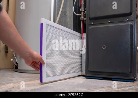 A person changing an clean air filter on a high efficiency furnace Stock Photo