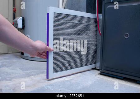 A person changing an air filter on a high efficiency furnace Stock Photo