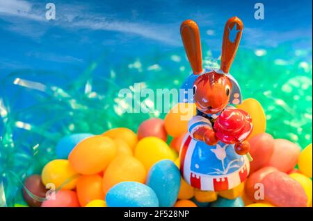 small wooden bunny resting on jelly beans Stock Photo