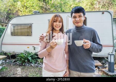 happy young couple drinking coffee in front of a camper RV van motorhome Stock Photo