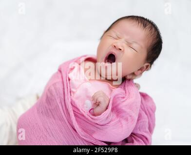 mother holding sleepy newborn baby yawning in her arm Stock Photo
