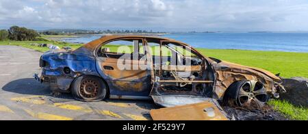 burnt out abandoned car at beach side beauty spot, Shellharbour, NSW Australia Stock Photo