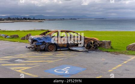 burnt out abandoned car at stormy beach side beauty spot, Shellharbour, NSW Australia Stock Photo