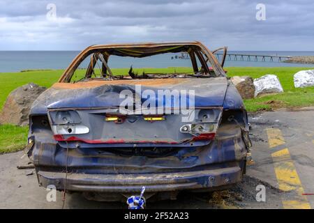 back view of burnt out abandoned car at beach side beauty spot, Shellharbour, NSW Australia Stock Photo