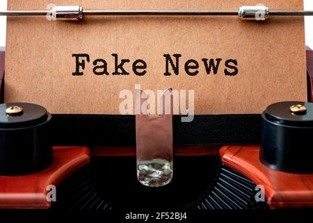 The dishonest media and unreliable newspapers concept with close up on a brown vintage typewriter with the text - fake news - written on yellow grungy Stock Photo