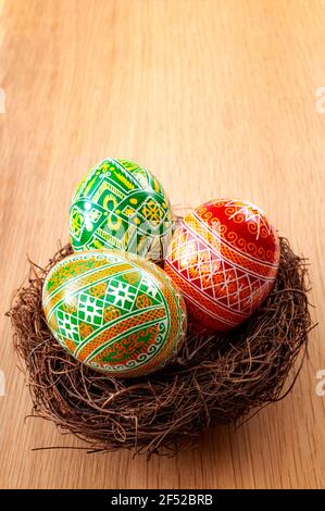 Easter holiday and spring celebration concept with three easter eggs decorated with a complex pattern in a birds nest isolated on a wood background wi Stock Photo