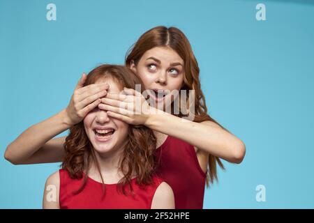 Mom and daughter in red dresses entertainment lifestyle fun studio blue background Stock Photo