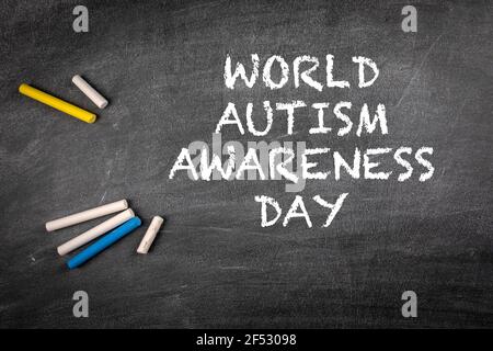 World Autism Awareness Day 2 April. Coloured pieces of chalk on a dark blackboard background. Stock Photo
