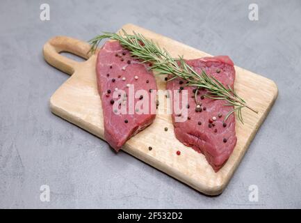 Raw beef steak with spices and rosemary on gray background Stock Photo