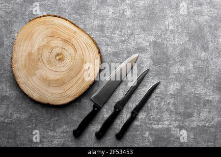 Wooden cutting bord  and 3 different knifes on gray concrete background. Stock Photo
