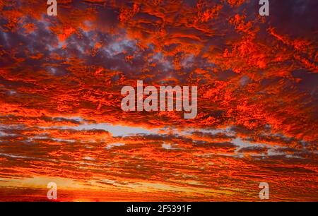 Stunning fiery red clouds at sunset in tropical North Queensland, Australia during monsoon season with vivid colors of reds and orange for background. Stock Photo