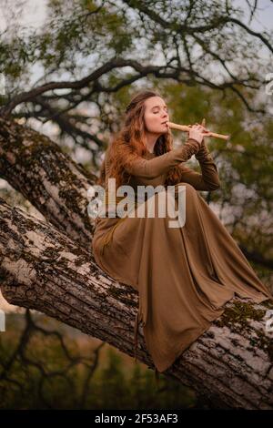 Redhead woman in dress walking in fantasy fairy tale forest Stock Photo
