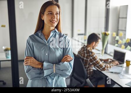 Pleased good-looking woman employee daydreaming in the workplace Stock Photo