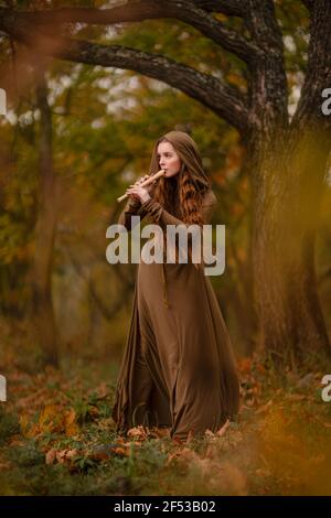 Redhead woman in dress walking in fantasy fairy tale forest Stock Photo