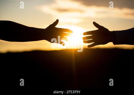 Friendly handshake, friends greeting, teamwork, friendship. Rescue, helping gesture or hands. Outstretched hands, salvation, help silhouette, concept Stock Photo