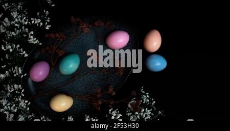 Pastel colored Easter eggs in a dark granite plate against Black background. Stock Photo