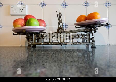 Vintage retro old kitchen iron kitchen scales with red and green apples and oranges on a granite kitchen bench.