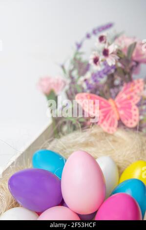 Colored Easter eggs and flowers in wooden white box with pink butterfly  on white background . Stock Photo