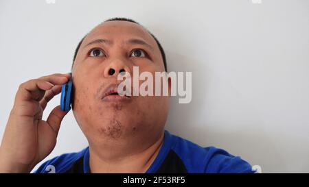 Asian man with bald hair is on the phone, with an old telephone with strange expression Stock Photo