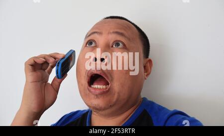 Asian man with bald hair is on the phone, with an old telephone with strange expression Stock Photo