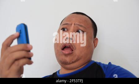 Asian man with bald hair is on the phone, with an old telephone with strange expression Stock Photo