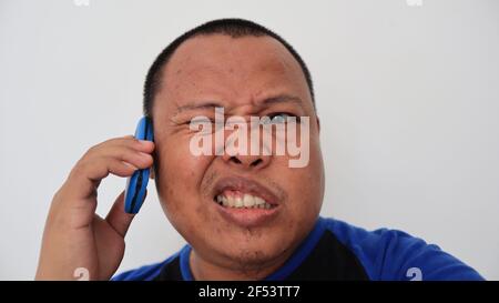 Asian man with bald hair is on the phone, with an old telephone with strange expression Stock Photo