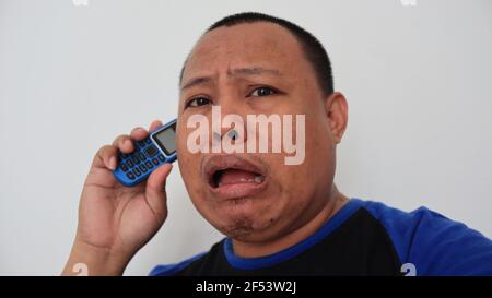Asian man with bald hair is on the phone, with an old telephone with strange expression Stock Photo