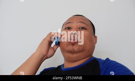Asian man with bald hair is on the phone, with an old telephone with strange expression Stock Photo