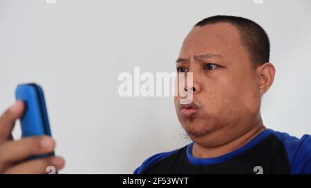 Asian man with bald hair is on the phone, with an old telephone with strange expression Stock Photo
