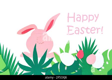 Easter creativity. Cut out paper rabbit, back view. Carved tropical leaves. The inscription "Happy Easter". Easter concept. Stock Photo