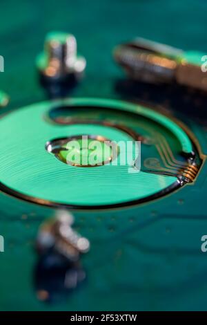 Macro photography  of hard drive internal mechanism hardware selective focus, in green blue light. Stock Photo