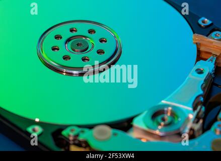 Macro photography  of hard drive internal mechanism hardware selective focus, in green blue light. Stock Photo