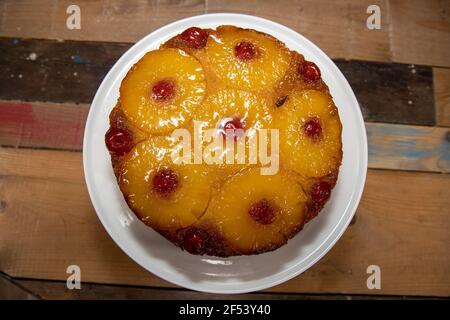 A delicious pineapple upside down cake on a wooden kitchen table Stock Photo